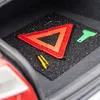 The image shows a set of car emergency tools laid out on a black rubber mat inside a car trunk. Náhľad obrázku produktu