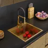 A modern kitchen sink with a gold finish, a black faucet, and fresh produce like tomatoes and figs. Produktbild-Vorschau