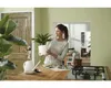 A woman is holding a potted plant in a kitchen. Produktbild-Vorschau