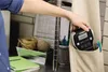 A person is putting a label maker into the pocket of an apron. Produktbild-Vorschau