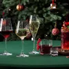 A festive Christmas scene with drinks on a green tablecloth in front of a decorated Christmas tree. Náhled obrázku produktu