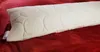 A long pillow lies on a red textured surface. Produktbild-Vorschau