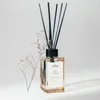 A glass diffuser bottle with reeds and a dried flower sprig. Podgląd zdjęcia produktu