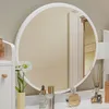 A vanity table with a round mirror and various cosmetic items on the surface. Náhľad obrázku produktu