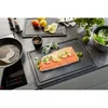 A kitchen counter with a salmon fillet prepared for cooking, along with other ingredients and cooking utensils. Podgląd zdjęcia produktu