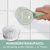 A hand holding a mint-colored electric cleaning brush against a tiled wall, with a separate brush head shown. Produktbild-Vorschau