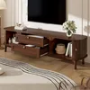 A dark wood TV stand with open shelves and drawers, placed in a living room setting. Voir les images du produit