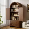 A wooden cabinet with open doors displaying books and decorative items, placed in a room with a white curtain and a sofa. Anteprima dell’immagine prodotto