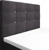 A close-up view of a dark gray upholstered headboard with tufted buttons and a white mattress topper. Náhled obrázku produktu