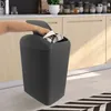 A hand is shown throwing trash into a dark gray trash can in a kitchen setting. Náhled obrázku produktu