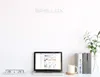 A desk setup with a laptop displaying an e-commerce website, a power strip, a mug, and books. Produktbild-Vorschau