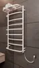 A white electric towel warmer is mounted on a dark gray tiled wall in a bathroom. A coiled white power cord connects the towel warmer to a wall outlet. Náhľad obrázku produktu
