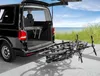 A black van with its tailgate open, parked on a paved surface near a grassy area and the ocean. Produktbild-Vorschau
