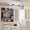 A luxurious living room with a large crystal chandelier, white furniture, and a built-in bookshelf with a television. Produktbild-Vorschau