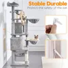 A multi-level cat tree with two cats on it, shown in a room with a white wall and a light-colored rug. Inset images show how to attach the cat tree to the wall for stability. Produktbild-Vorschau