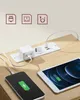 A white power strip with a power adapter, phone, and tablet charging on a wooden surface. Náhled obrázku produktu
