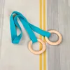 Two wooden rings with turquoise straps are laid out on a striped fabric background. Voir les images du produit