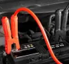 A close-up view of a car battery with red jumper cables attached to the terminals. Podgląd zdjęcia produktu