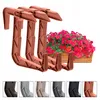 A set of terracotta-colored balcony planter holders with a planter box filled with pink flowers in the background. Náhľad obrázku produktu