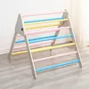 A wooden climbing triangle with colorful bars, set up indoors on a wooden floor. Voir les images du produit