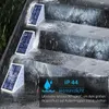 Drei weiße Solar-Treppenleuchten mit blauen Solarmodulen auf Außentreppen, mit Wasserspritzern zur Demonstration der Wasserdichtigkeit Náhľad obrázku produktu