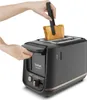 A person is using tongs to place a slice of bread into a black toaster. Voir les images du produit