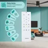A remote control for a ceiling fan is shown in front of a modern living room with a ceiling fan installed. Náhled obrázku produktu