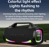 A black portable speaker with colorful LED lights is shown on a table outdoors. Produktbild-Vorschau