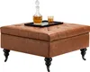 A square leather ottoman with tufted top and decorative nailhead trim sits on black legs with casters. A decanter and glass of amber liquid are on a black tray on top of the ottoman. Anteprima dell’immagine prodotto
