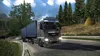 A truck driving on a road through a forest. Produktbild-Vorschau