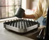 A person is placing a gray cup onto a drying rack. Voir les images du produit