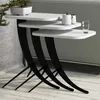 A set of three white nesting tables with black curved legs, displayed on a light-colored floor against a gray wall. Produktbild-Vorschau