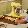 A person is braiding dough next to a yellow stand mixer. Produktbild-Vorschau