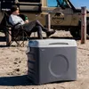 A man sits in a camping chair next to a cooler and a vehicle. Produktbild-Vorschau