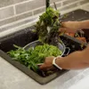 Hands washing leafy greens in a kitchen sink. Anteprima dell’immagine prodotto