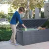 A woman is putting items into a large outdoor storage box. Produktbild-Vorschau