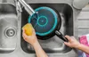 A person is washing a frying pan in a kitchen sink. Produktbild-Vorschau