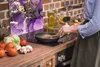 A person is cooking in a kitchen, with a glass splashback behind the stove. Náhled obrázku produktu