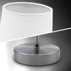 A close-up studio shot of a modern table lamp with a white fabric shade and a brushed metal base. Podgląd zdjęcia produktu