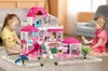 Two young girls playing with a large pink dollhouse in a living room. Voir les images du produit