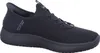 A black Skechers slip-on shoe is shown from a side view against a white background. Voir les images du produit