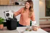 A woman is adding ingredients to a bread maker in a kitchen. Náhľad obrázku produktu