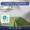 A table setting with a white tablecloth and green underlay, featuring plates and cutlery. Produktbild-Vorschau