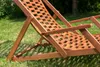 A wooden deck chair is placed on a grassy lawn. Podgląd zdjęcia produktu