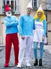 Three people in Smurf costumes standing on a cobblestone street. Produktbild-Vorschau