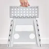 A person is holding a folded gray plastic step stool. Náhľad obrázku produktu