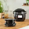 A black Tefal Cook4me Extra Crisp appliance is shown on a wooden countertop, with a smaller accessory in the foreground and jars of food in the background. Produktbild-Vorschau