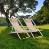 Two beige and white deck chairs are set up on a lush green lawn under a large tree, with a backdrop of more trees and a clear blue sky. Produktbild-Vorschau