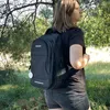 A person wearing a backpack in a wooded area. Náhled obrázku produktu