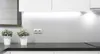 A modern kitchen counter with under-cabinet lighting, two potted plants, and an electrical outlet. Produktbild-Vorschau